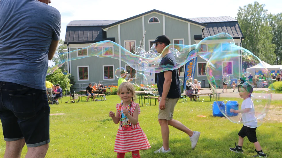 Henning Andersson och barnbarnet Klara Lundström blåser bubblor i parken.