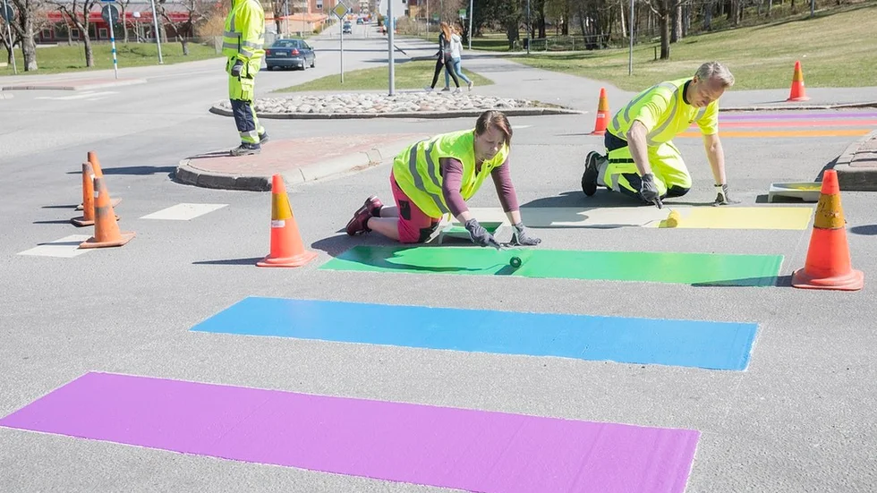 Anneli Hedberg (S), nämndordförande, och Magnus Gustafsson, förvaltningschef på service och teknik, hjälpte till att förvandla ett vanligt övergångsställe vid Tallåsaulan till ett regnbågsfärgat konstverk.