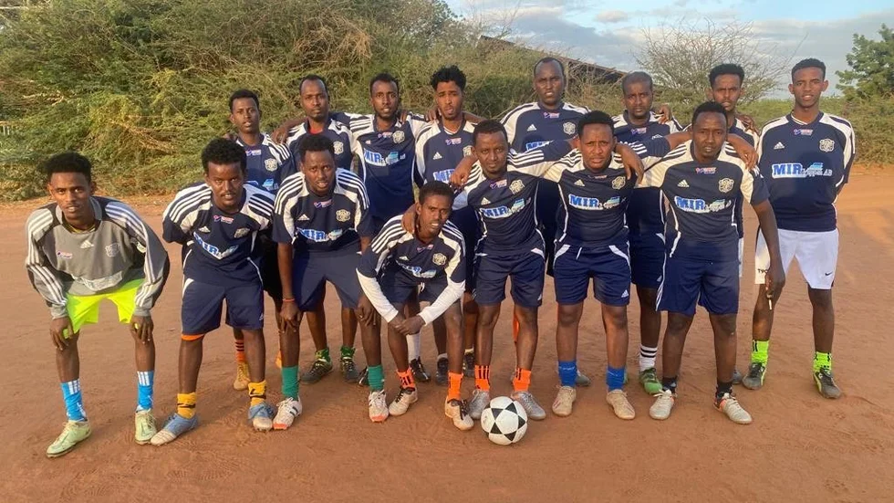 Hussni Ahmed som står bakom bollen har lämnat fotbollsutrustning från Vimmerby IF i ett stort flyktingläger i norra Kenya.