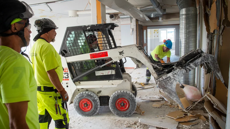 Till sin hjälp med rivningen har en bobcat som har lyfts upp till andra våningen.
