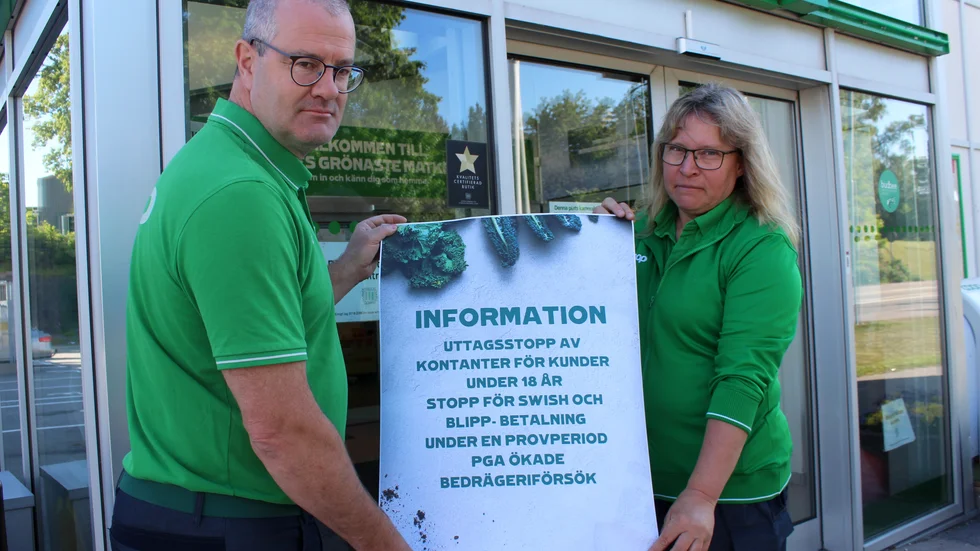 Coop Finspångs vd Anders Svensson och Bergslagshallens butikschef Susanne Stelzl sätter upp skylten som informerar om att de slutar med betalningar med swish och blipp samt uttag av kontanter för personer under 18 år på grund bedrägerier.