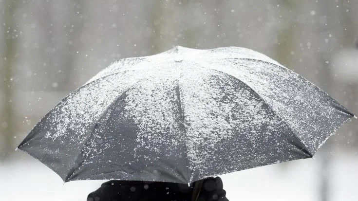A person  uses an umbrella during snowfall in Berlin, Tuesday Jan. 21, 2014. Weather forecasts predict changeable weather  for Germany.  (AP Photo/dpa, Maurizio Gambarini)