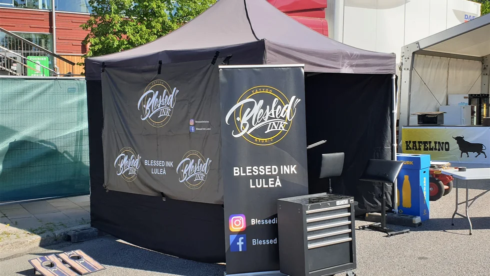 Här, intill ett av pubtälten på festivalområdet Putte i parken i Luleå, sköter Blessed Ink som sin verksamhet under stadsfesten.