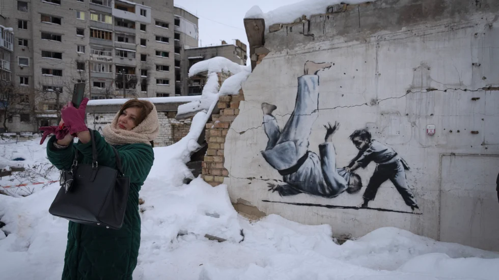 En kvinna tar en selfie vid ett konstverk skapat av brittiska Banksy i Kievregionen i december 2022.