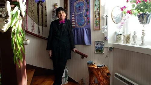 Anne-Britt Cranser, elegant i egenhändigt sydda kläder, tar emot i sin trappuppgång som är fylld av konstverk som hon skapat med egna händer.