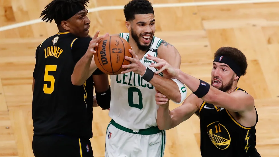 Bostons Jayson Tatum i närkamp med Golden States Kevon Looney och Klay Thompson.