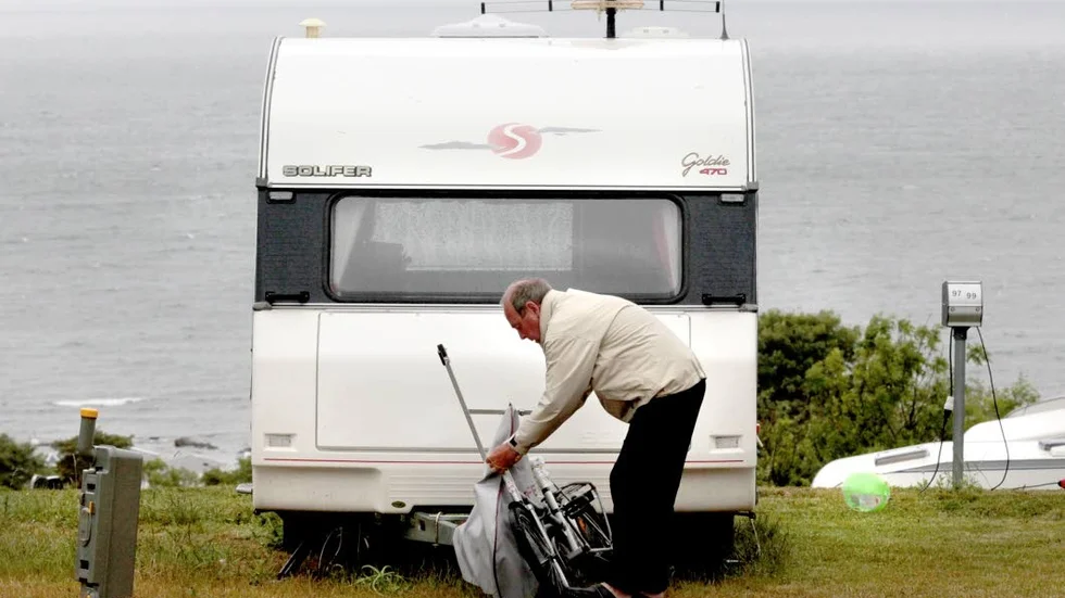 Bengt Nilsson från Staffanstorp klär cykeln i regnskydd utanför husvagnen på Snäcks camping.