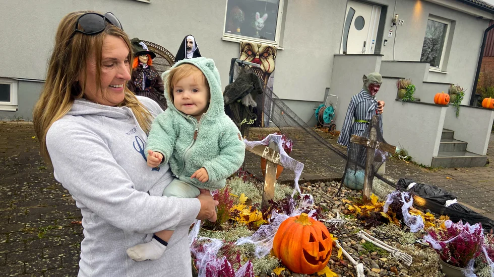Anette Nordén med barnbarnet Lilly i famnen framför det Halloween-smyckade hemmet. 
