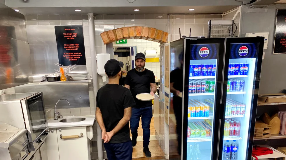 Tashfeen Mahmood hämtar en pizza i form från kylen som sedan ska tillagas i ugnen.