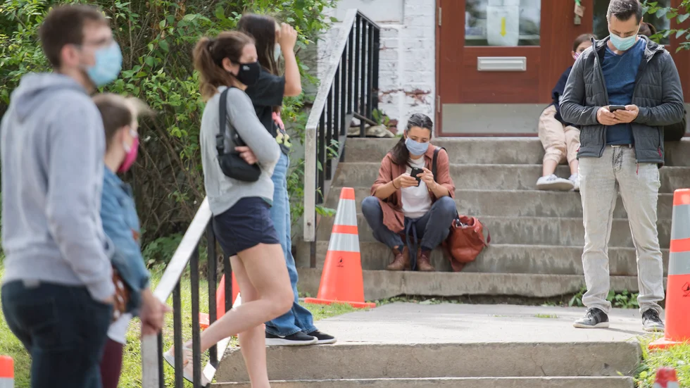 Människor med munskydd utanför en testklinik i Montréal.