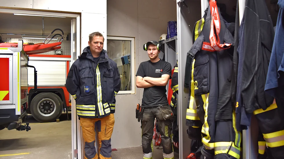 Rimforsa brandstations platschef Karl-Johan Bönner och vvs-montören Gustav Kull framför den nybyggda väggen. "Idag jobbar vi med att koppla om lite vatten",  berättar Kull. 