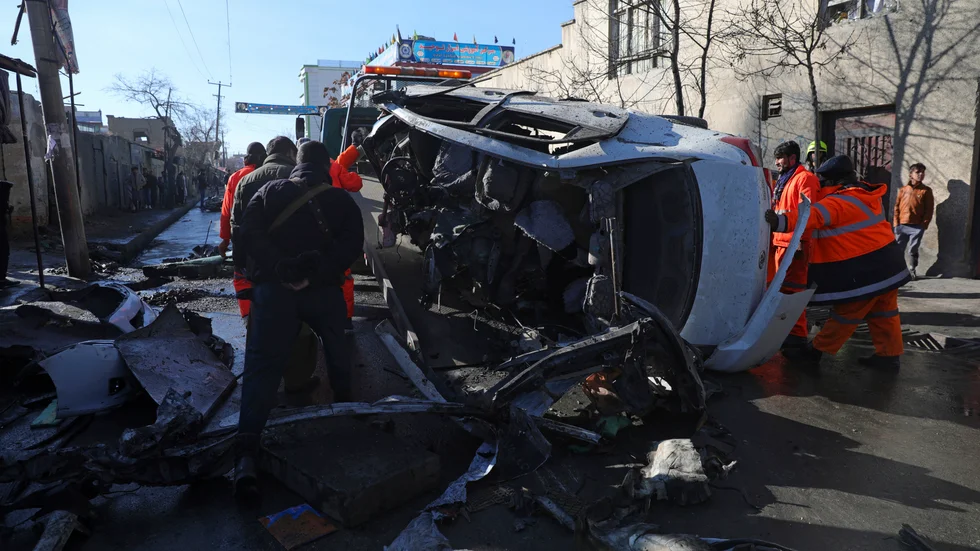 Säkerhetsstyrkor och kommunalarbetare flyttar en demolerad bil efter tisdagens bombdåd i Kabul.