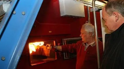 Tommy Söderlund från tillverkaren Osby Parca satte fyr i pelletspannan med en bit brinnande kartong. Stig Eriksson, vd för Tierps Fjärrvärme, övervakade.