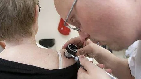 Med ett så kallat detmatoskop undersöker hudläkaren Per-Håkan Olausson en brun fläck på Margareta Brunns axel.