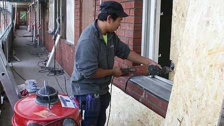Håkan Strömberg från företaget Saneringsentreprenad sätter för fönstergluggarna till huset med spånskivor. Torkfläktar har stått på sedan april för att få bort all vatten efter släckningsarbetet.