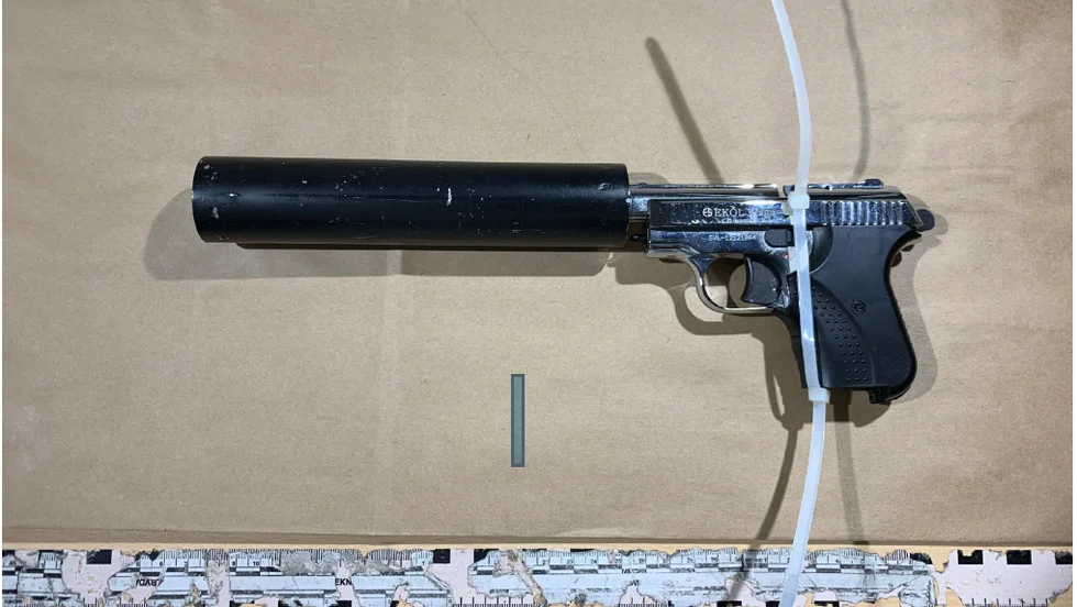En halvautomatisk pistol med ljuddämpare hittades liggande på en bänk i mannens bostad.