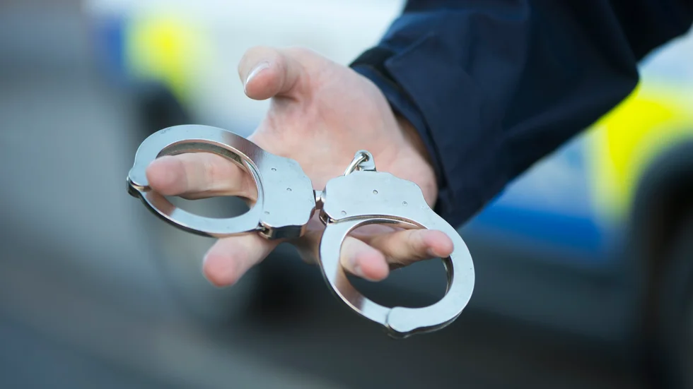 Den aggressive och fulla bilföraren fick ha på sig handbojor. Men även dubbla fotbojor och spotthuva krävdes när han kördes till akuten för blodprovstagning.
