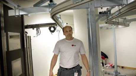 Robert Samarzija står inne i automaten. Till vänster syns luckan där datorskärmarna ska sitta. Kläderna ska färdas längs skenorna. FOTO: KURT ENGSTRÖM FOTO: Kurt Engström