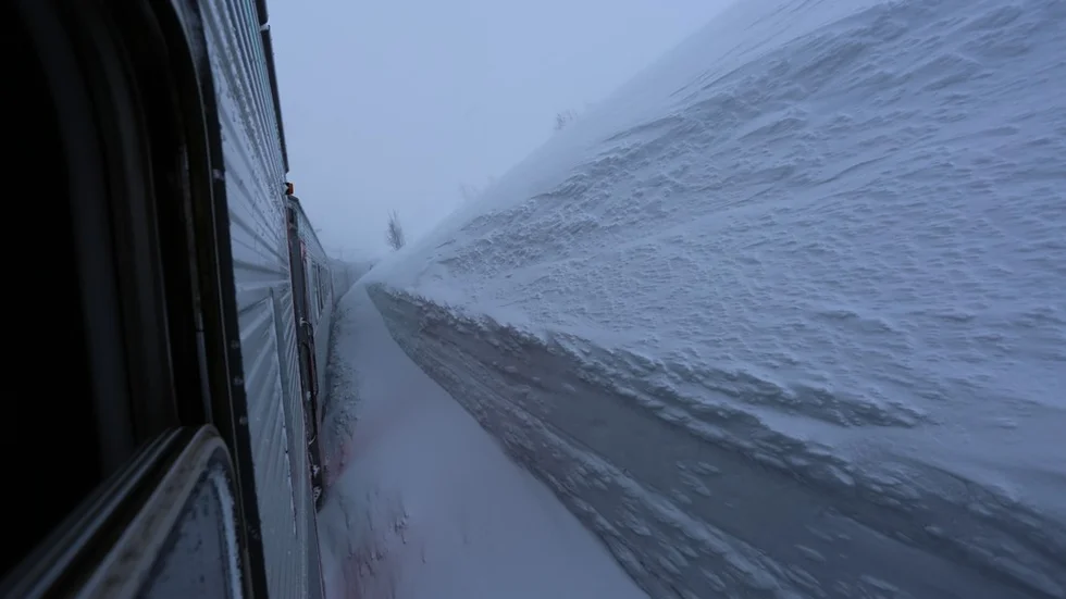 Läsarbilden visar det kraftiga snödrevet där SJ:s passagerartåg har fastnat i Katterjokk. Hoppet står till att LKAB:s malmlok ska lyckas bogsera loss passagerartåget.