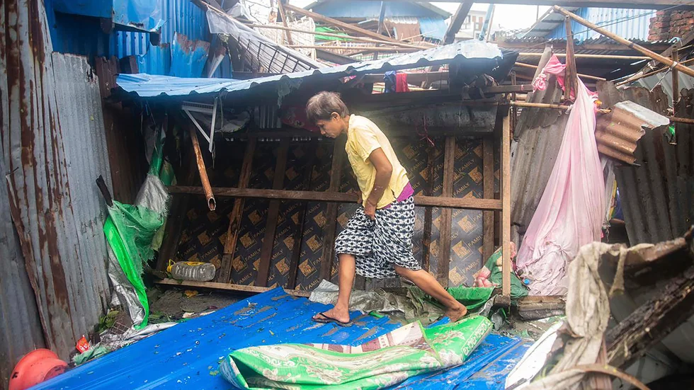 En kvinna går förbi skadade byggnader i delstataten Rakhines huvudstad Sittwe.