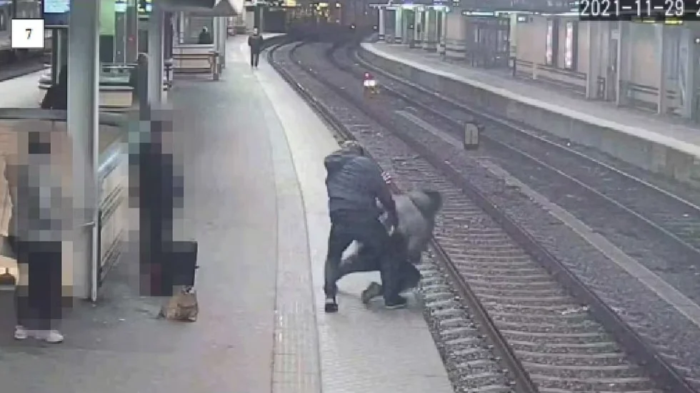 En övervakningskamera visar hur Umeåbon greppar tag i den andre mannen bakifrån och kastar ned honom på tågspåret.
