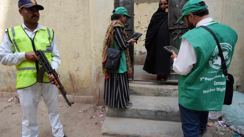 En polis håller vakt medan en utsänd från statistikmyndigheten samlar uppgifter från en kvinna under folkräkningen i Peshawar i Pakistan i år.