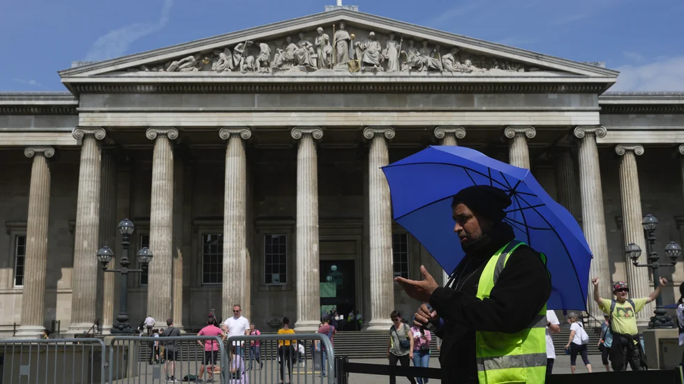 A worker holding an umbrella guides the tourists at British Museum during a hot weather day in Central London, Monday, June 12, 2023. (AP Photo/Kin Cheung) XKC103