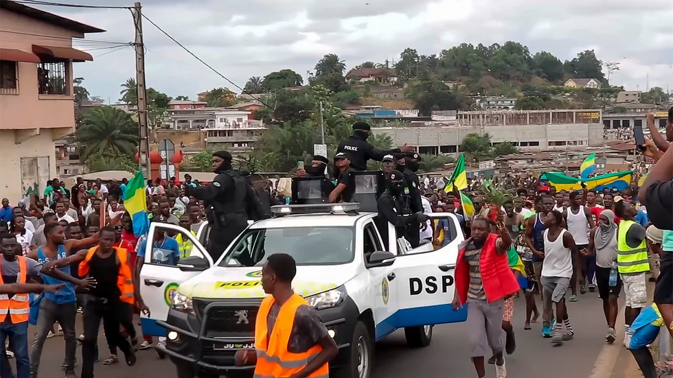 Jublande människor följer poliser genom Gabons huvudstad Libreville på onsdagen.
