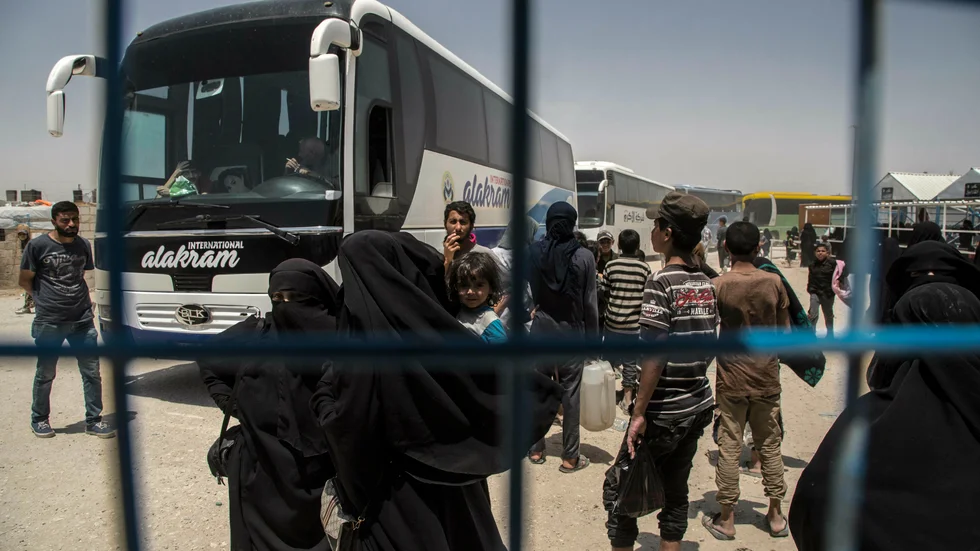 Kvinnor och barn väntar på bussar vid Al-hol-lägret i Syrien. Arkivbild.