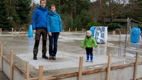 Tim och Anna Essius med sonen Theo på sin tomma husplatta i Ljunghusen. Familjen har noga valt till energisnåla fönster och dörrar till sitt hus och planerat sitt hem för framtiden.