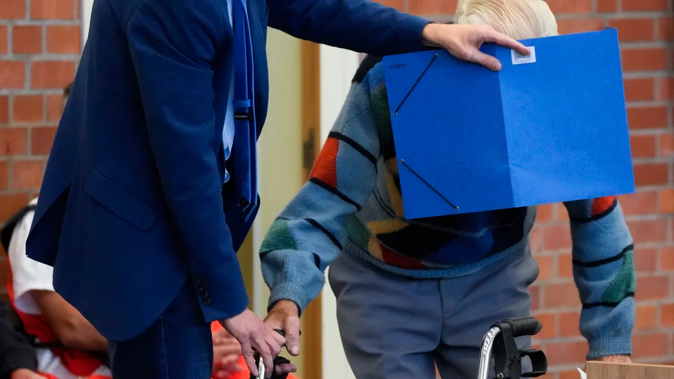 Mannen, då 100 år, försökte dölja sitt ansikte under rättegången.