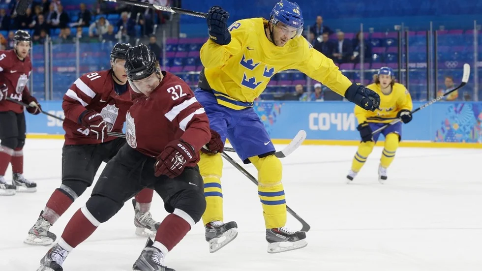 Latvia defenseman Artus Kilda and Sweden forward Jimmie Ericsson chase a loose puck during the 2014 Winter Olympics men's ice hockey game at Shayba Arena Saturday, Feb. 15, 2014, in Sochi, Russia. (AP Photo/Mark Humphrey)