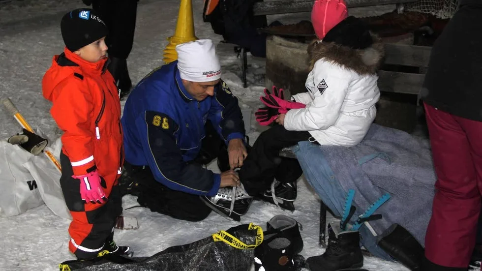 Påtagning. Här hjälper Andreas Karlberg Elsa på med skridskorna. Killen i orange overall är Gabriel Karlberg.