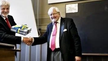 Tore Frängsmyr, professor i vetenskapshistoria vid Uppsala  universitet, överlämnar boken om universitetes historia till rektor Anders Hallberg.