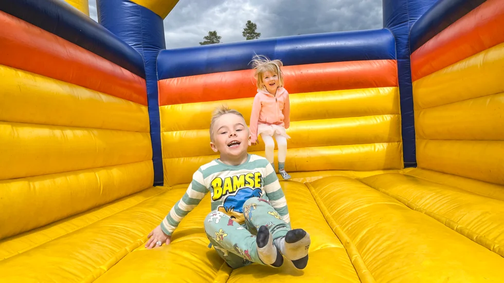 På Sikfors Fiskefestival finns rum för både fiske och lek. Tage Ermebring, 5 år och Miri Skarin, 4 år, hoppar i hoppborgen. När energin så småningom tryter väntar sockervadd.