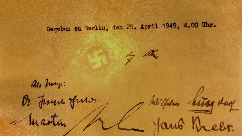 Dokumentet är signerat av Adolf Hitler i mitten av bilden. Nedanför finns underskrifter av vittnena Joseph Goebbels och Martin Bormann,                                                båda nazipolitiker, samt generalerna Wilhelm Burgdorf och Hans Krebs.