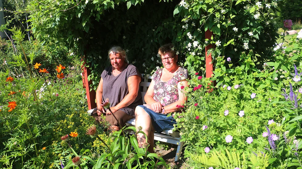 Då och då  kan det vara skönt att sätta sig ner en stund och pusta. tycker Lotta Rosander och Lena Axelsson. Gärna då i den vita soffan i skuggan under den stora Clematisbusken.
