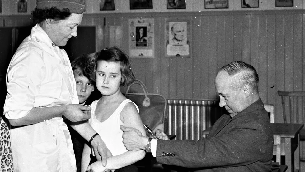 I februari 1957 inleddes poliovaccineringen i Linköping. Läkaren Gösta Arnwald och syster Rakel Ekström ses här vaccinera Gunilla Svensson i Hjulsbroskolan.