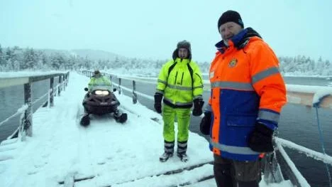 Nu är skoterbron över Arjeplogsströmmarna farbar. Bert Sundstén testkör. Per Nilsson och skoterföreningens ordförande Lennart Löfgren konstaterar: "Den håller".