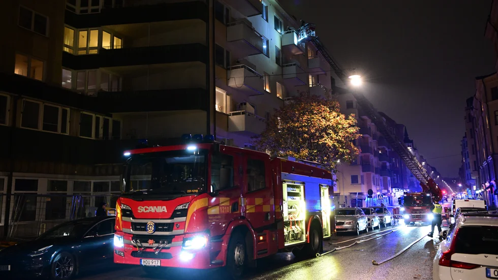 Räddningstjänsten vid ett lägenhetshus i Vasastan i Stockholm som eldhärjades under lördagskvällen. Fyra personer fick rökskador, varav tre fördes till sjukhus.