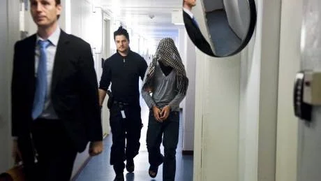 Den 18-årige ynglingen förs in till häktningsförhandlingen där han via sin advokat David Boberg (i förgrunden) förnekade brott.