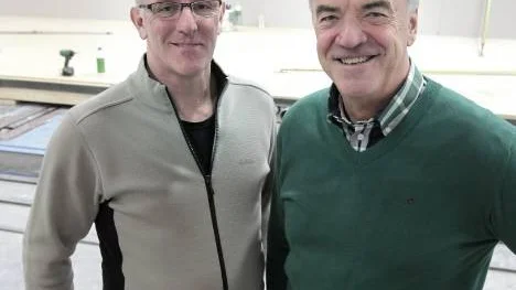 Glada miner hos Wilhelm Risberg och Erik Lindbäck åskådliggör det senaste "kapet" - en affär värd 320 miljoner kronor för Lindbäcks Bygg.
