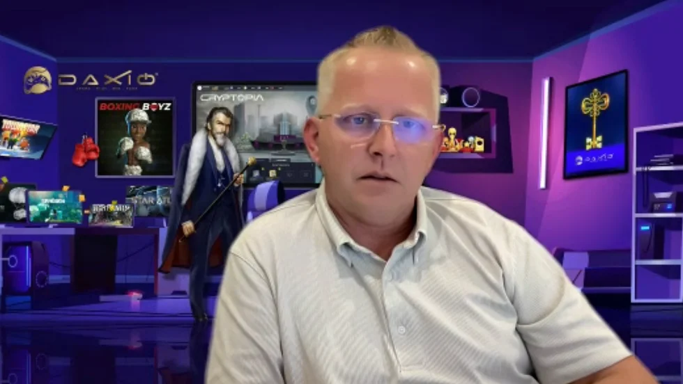 Frode Jørgensen har lagt in en egen bakgrundsbild bakom sig. Bilden föreställer ett rum med lila neonbelysning. I bakgrunden syns spelkonsoler, samlarfigurer och en dator.