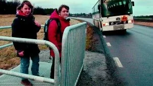 Olivia Zetterblom och kompisen Olivia Martinz i väntan på skolbussen i den nya mobila hållplatsen vid Djurövägen. Olivia Zetterblom berättar att hon åker med bussen när den vänder vid Djurön på vägen hem från skolan, för att säkert och tryggt kunna kliva av på den sida av vägen hon bor. FOTO: ANITA KJELLBERG