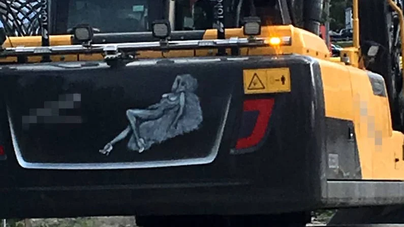 En bild av en naken kvinna på en grävmaskin upprör.