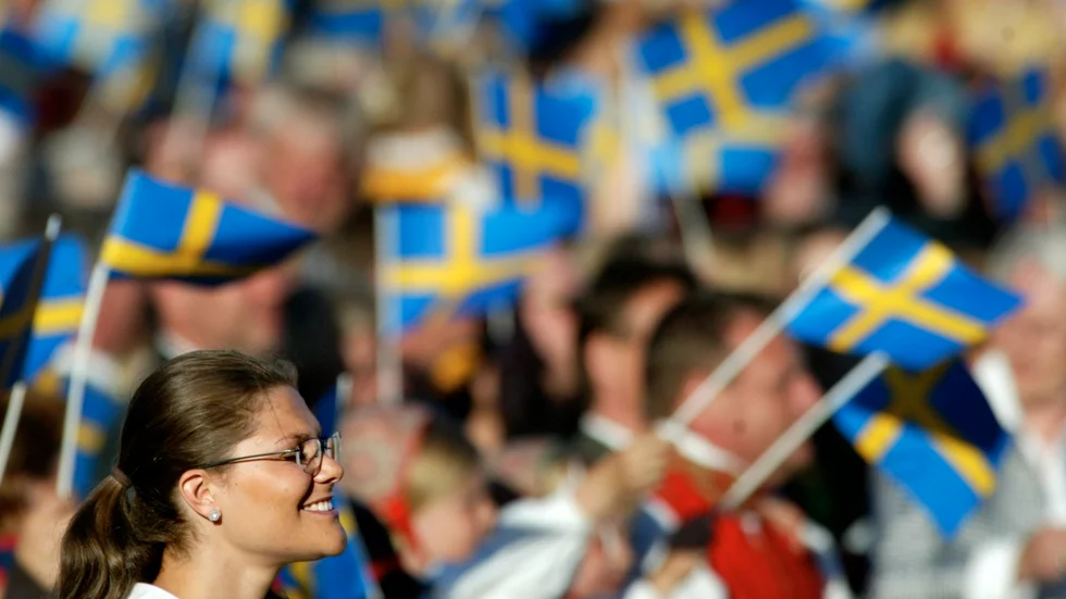 Bilden är tagen under ett av mellanåren. Svenska flaggans dag hade hunnit bli Sveriges nationaldag, men kronprinsessan har ännu ett leende på läpparna. Föga anar hon att riksdagen är på väg att avskaffa annandag pingst för att göra helgdag av 6 juni, på bekostnad av hela den svenska identiteten.