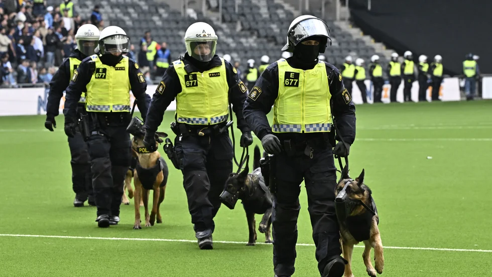 Poliser med hundar och kravallutrustning lämnar planen under söndagens fotbollsmatch i allsvenskan mellan Djurgården och AIK på Tele2 arena i Stockholm.