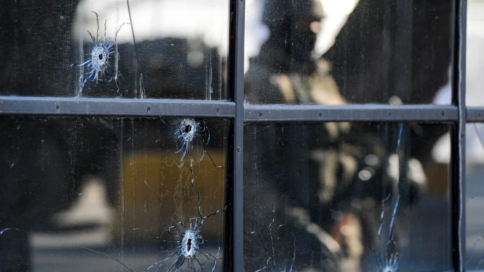 Skotthål i fönstret till en butik i Almaty i Khazakstan. I reflektionen syns en kazakstansk soldat som håller vakt. Bilden är från i fredags.