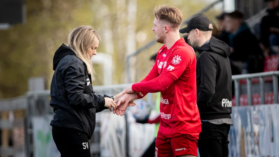 Fysioterapeuten Sofia Viklund ser över Fredrik Johanssons skadade handled. Tränaren Tomas Eriksson avvaktar i bakgrunden.
