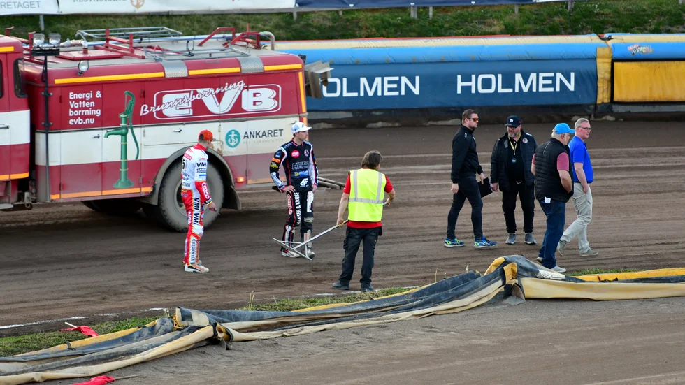 Banan i Hallstavik inspekteras av bland andra lagkaptenerna Kim Nilsson (t v) i Rospiggarna och Indianernas Niels-Kristian Iversen. Bilden är tagen klockan 20.42. nästan en timme efter avbrottet.